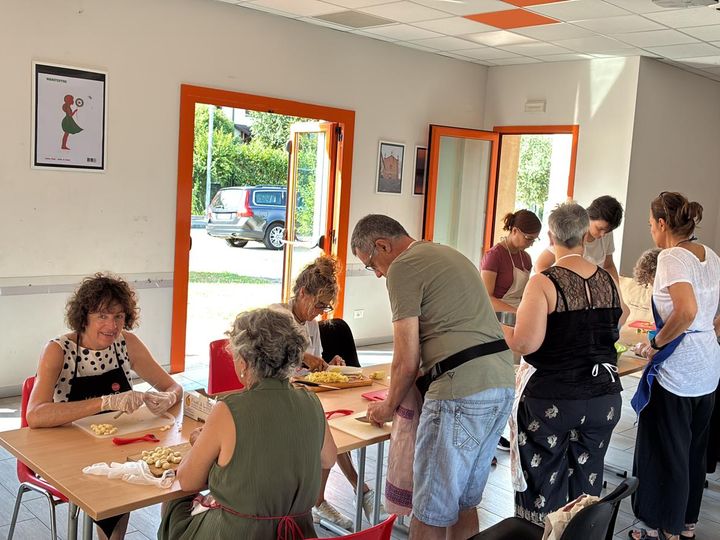 Volontarie e volontari al lavoro sui taglieri, in una sala luminosa.