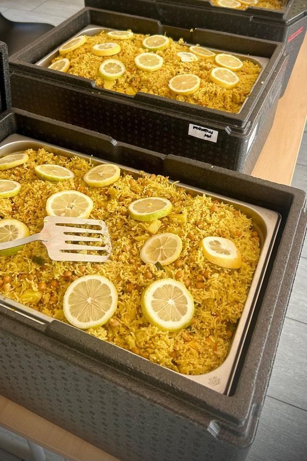 Teglie di riso con fette di limone, pronte nei contenitori termici.