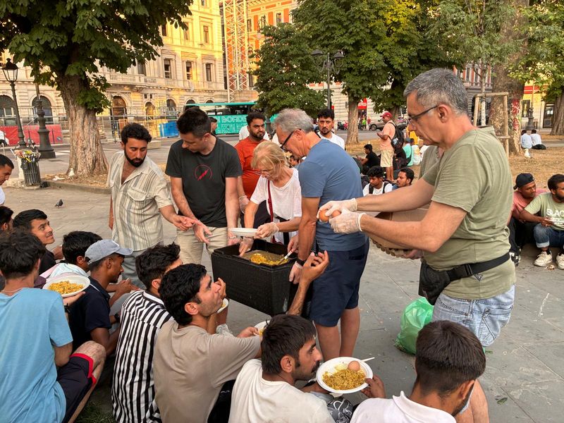 I volontari distribuiscono riso e uova sode ai ragazzi seduti attorno a loro.
